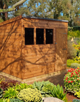 Shiplap pent shed installed in a garden setting surrounded by plants and flowers