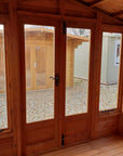 Interior of Elkington summer house with open glazed doors showing timber frame construction and garden view
